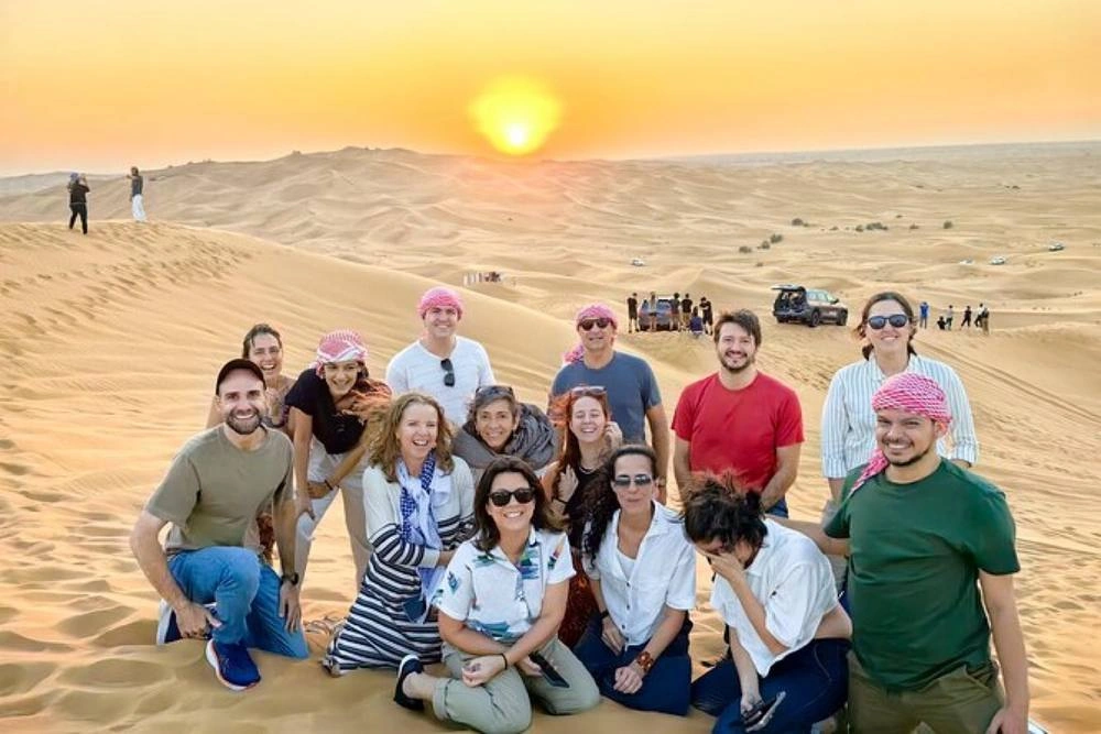 Guests on Dubai desert dunes at sunset
